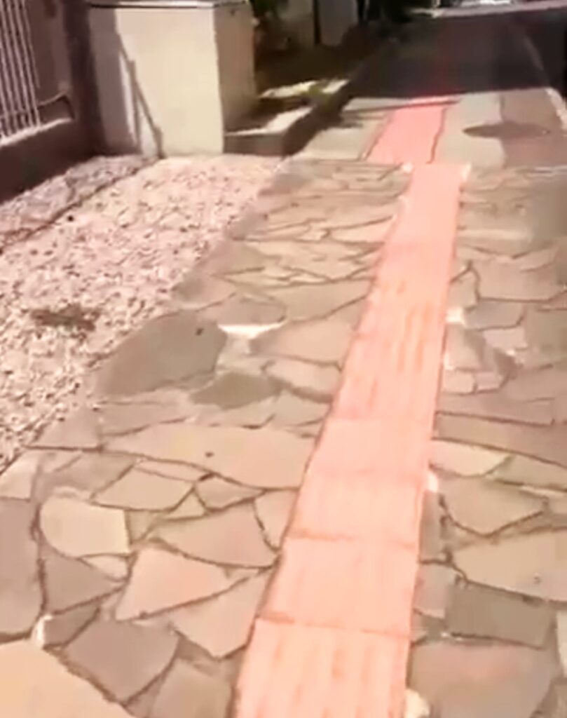 A imagem mostra o piso tátil direcional e ao lado um piso de pedras de diferentes tamanhos