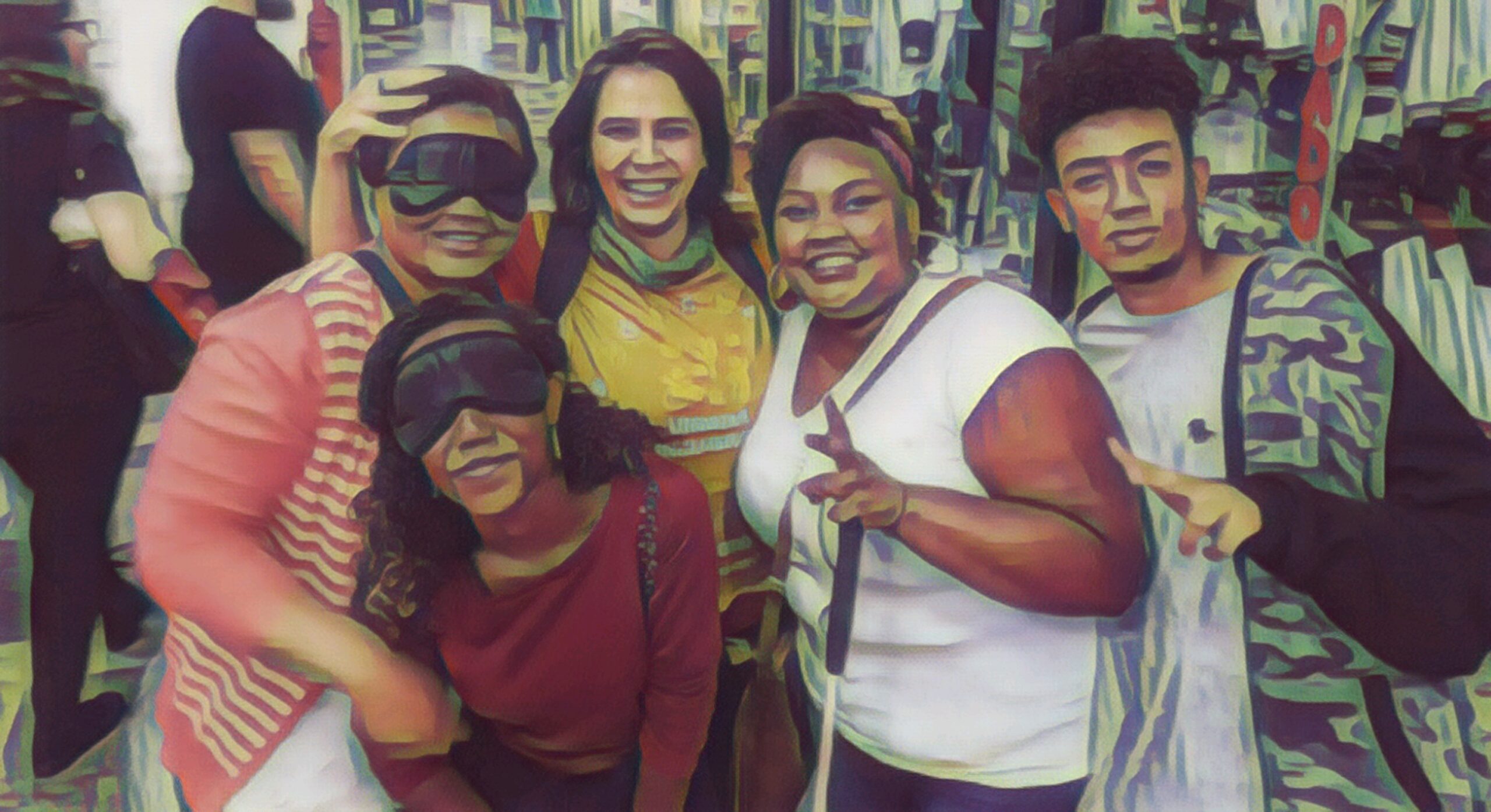 A imagem mostra um grupo de pessoas que parecem estar em alguma vivência, pois 02 mulheres estão com vendas nos olhos. Eles posam para a foto. Entre eles está uma mulher que abraça o grupo. Dois jovens (um rapaz e uma moça com bengala longa) fazem um gesto de "V" com os dedos.